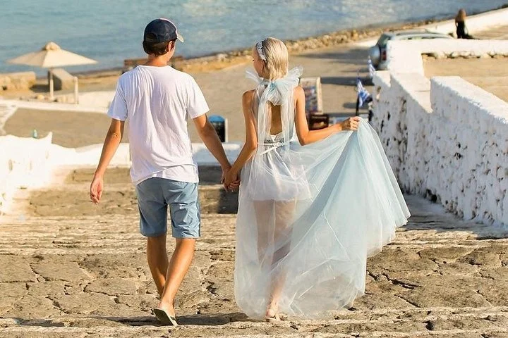 Couple walking hand in hand down whitewashed steps by the sea during a Mykonos photo session
