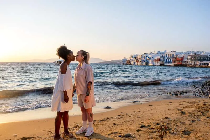 Two partners laughing under bougainvillea in a whitewashed alley on a couple Mykonos photoshoot