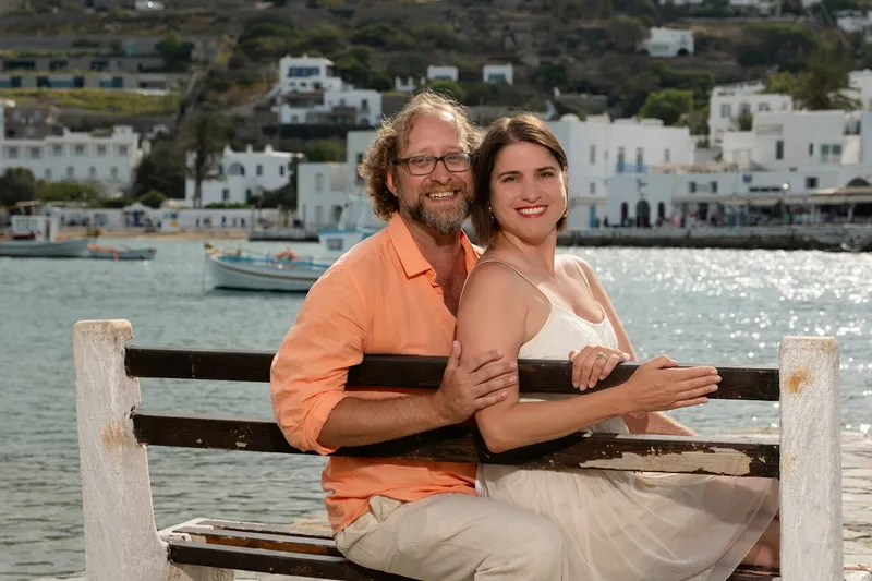 Couple walking hand in hand past the Windmills of Mykonos on a Mykonos photoshoot walking tour