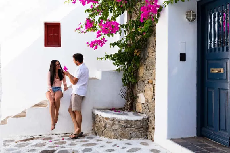 Woman framed by a blue door and bougainvillea in Chora on a Mykonos Town photoshoot